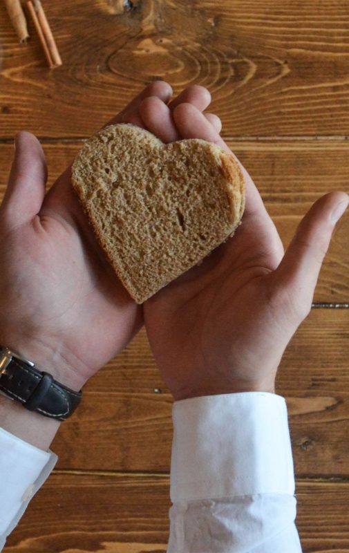 man holding a heart shaped piece of bread